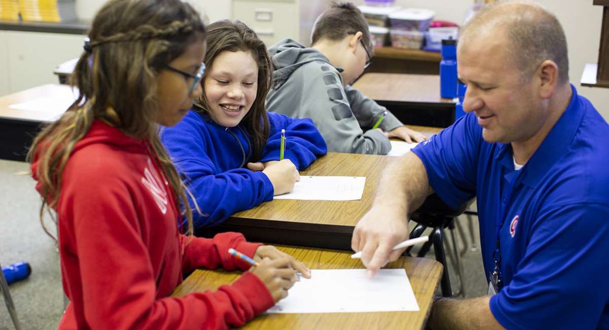 Teacher helping students at a desk