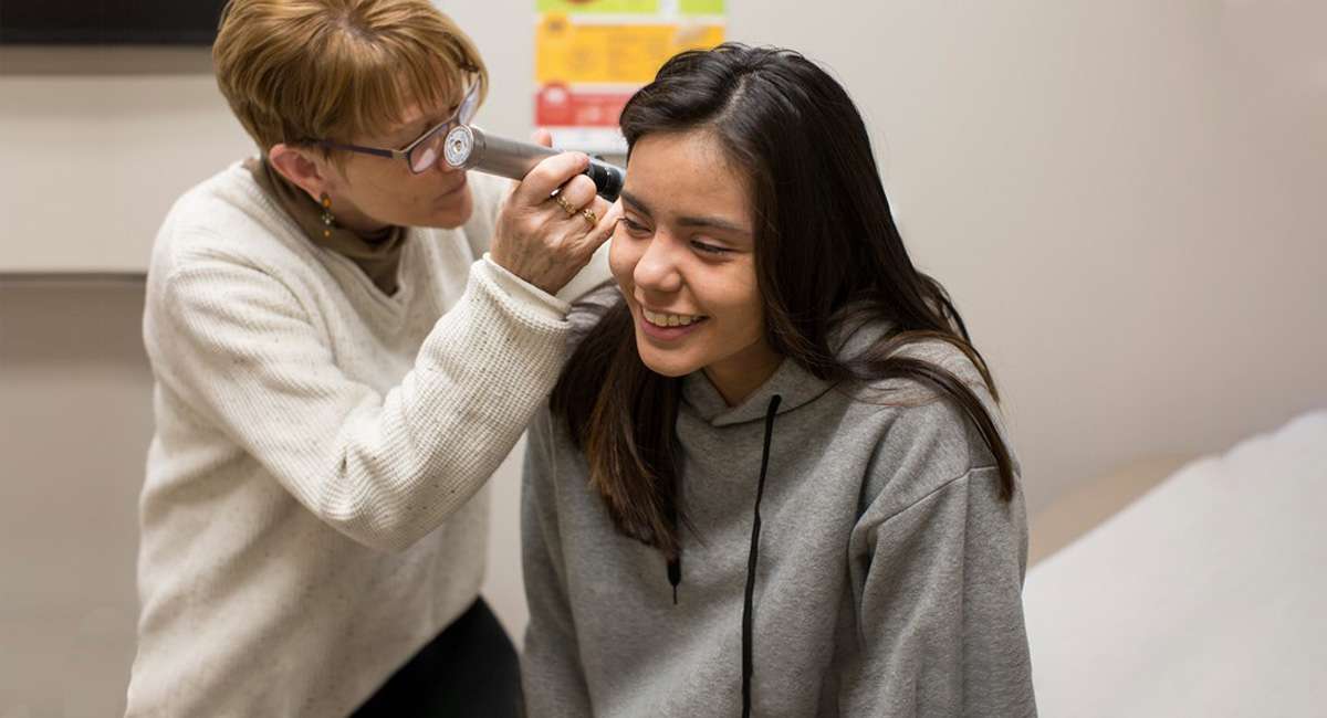 Nurse looking into students ears