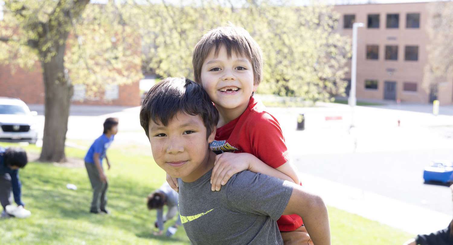 Student giving younger student a piggy back ride