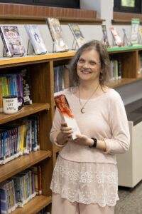 Claire Nehring poses with the School Achievement Through Libraries (SATL) Distinguished School Librarian Award in the St. Joseph's Indian School Library. 